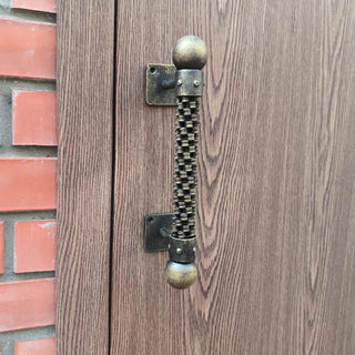A handmade industrial door handle made from a repurposed bicycle chain, featuring a rugged, steampunk design. Ideal for rustic and modern decor, this metal door pull adds a unique, durable touch to any door.