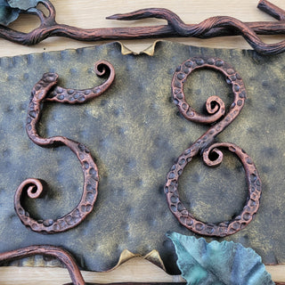 Macro detail of the number “5” showing forge marks and curled tail.
Macro detail of the number “8” with hammered pattern and scroll design