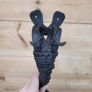 Detailed close-up of the hand-sculpted bull head on a forged iron handle, showing expressive eyes and curved horns.