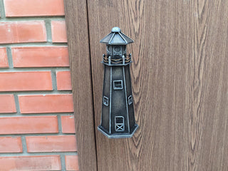 A vintage-style metal lighthouse door handle in a nautical theme, perfect for rustic and coastal home decor. Ideal for beach houses or cabins, this durable handmade door pull adds charm and function to any door.