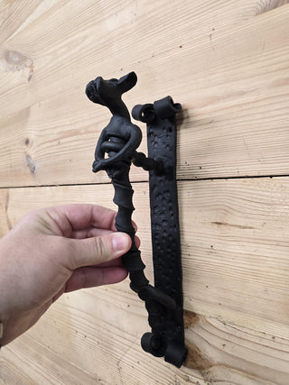 Iron door handle shaped like a seated dog with curled tail.