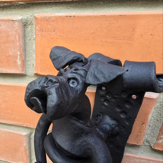 Artistic and rustic dog-shaped door pull mounted on vertical surface.