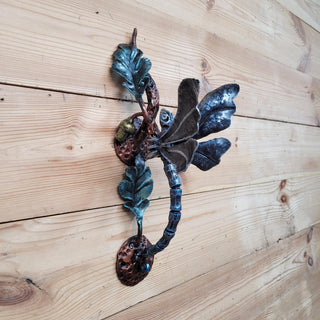 Hand-forged dragonfly door handle on oak branch