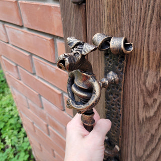 Handcrafted wrought iron dog door handle with antique brass finish, perfect for vintage and rustic style doors.