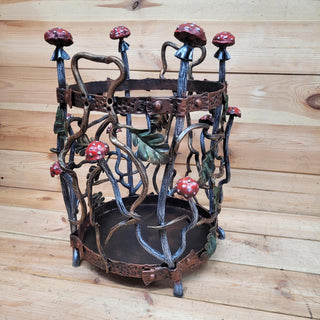 Hand-forged wrought iron firewood rack with mushrooms and oak leaves, front view.