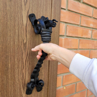 Forged iron bull head handle attached to a rustic barn door, showing the full shape and mounting brackets.
