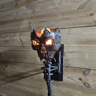 Close-up of handmade metal skull lamp glowing with orange light