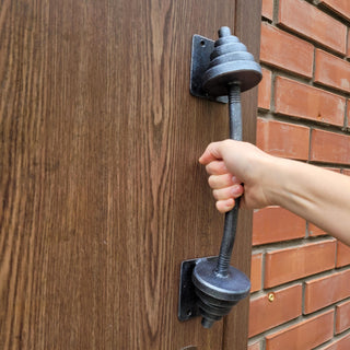 Handmade metal dumbbell door pull with unique blacksmith craftsmanship, designed for lasting durability.