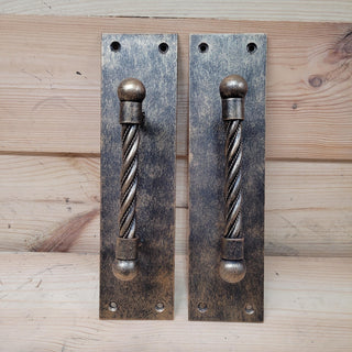 Rustic wrought iron door pulls with a twisted design, ideal for barn doors and industrial decor.